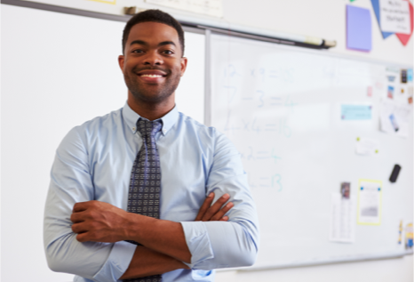 African American make smiling, standing with arms crossed in front of dry erase board